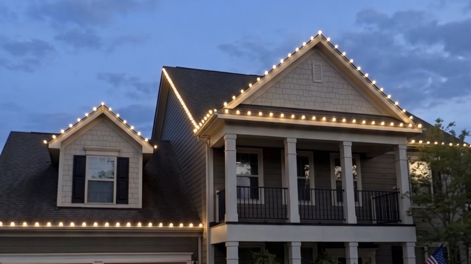 Christmas lights outlining the rooflines of a house at dusk
